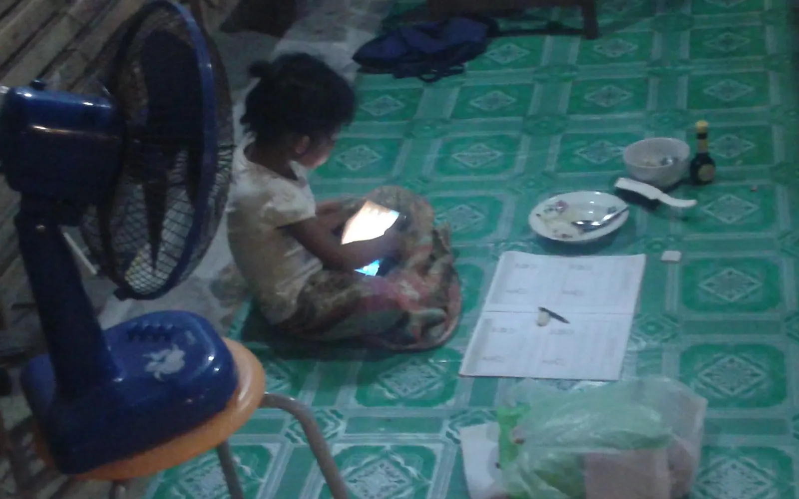 A child sitting on the floor, using a tablet