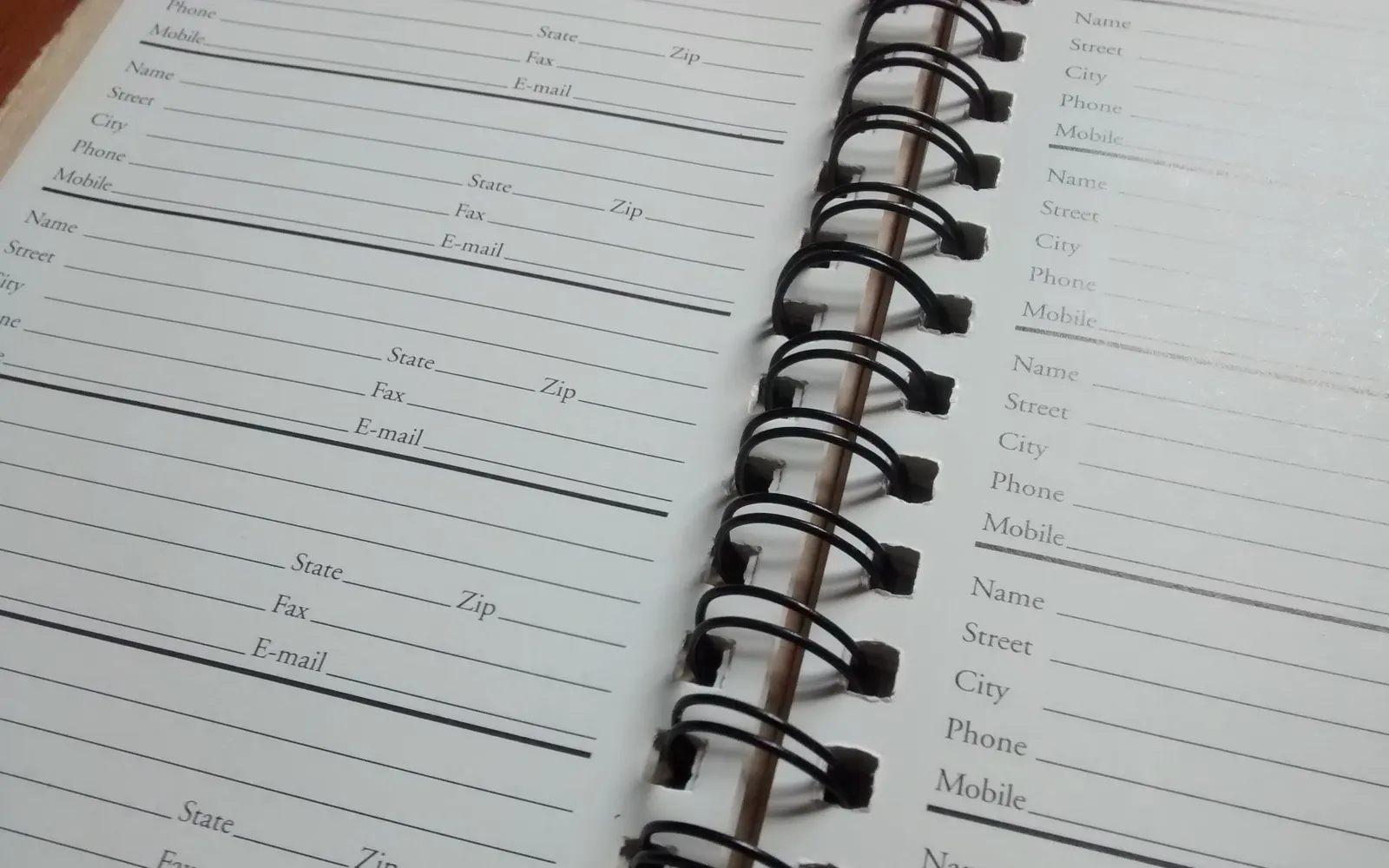 An open address book with blank contact entries on a spiral-bound page