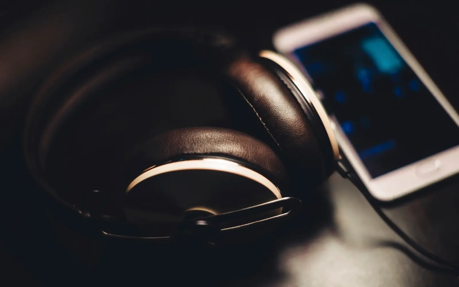 Over-ear headphones resting beside a smartphone in low light
