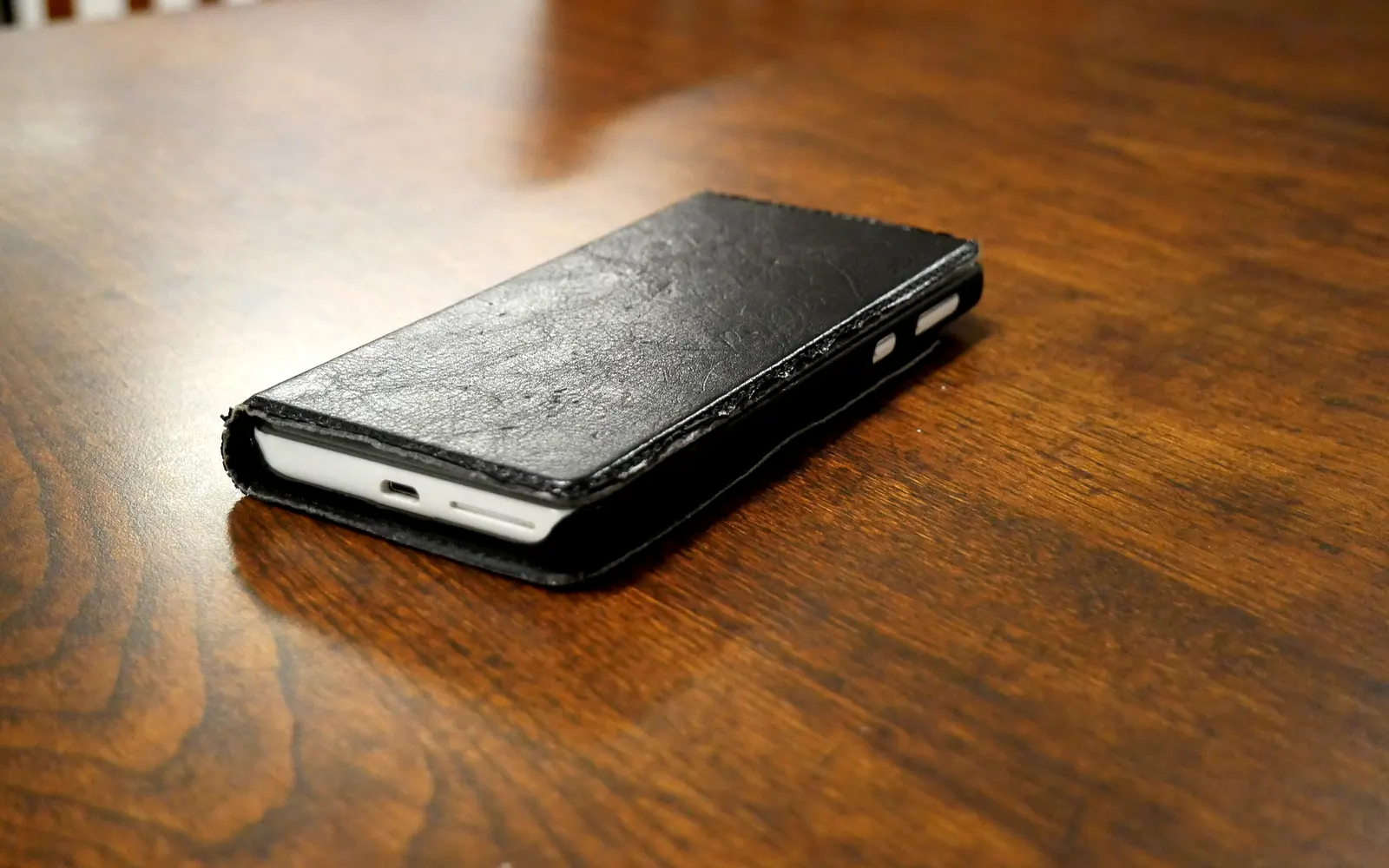 A smartphone closed inside a flip case, resting on a wooden table