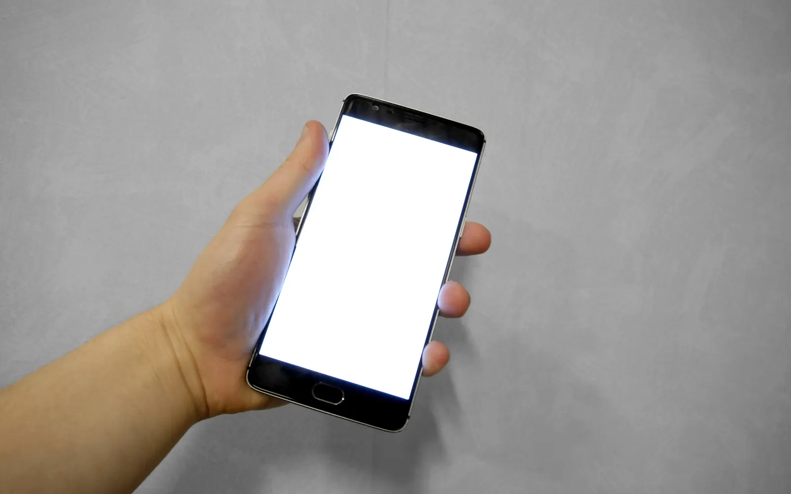 A hand holding an Android phone with a blank screen