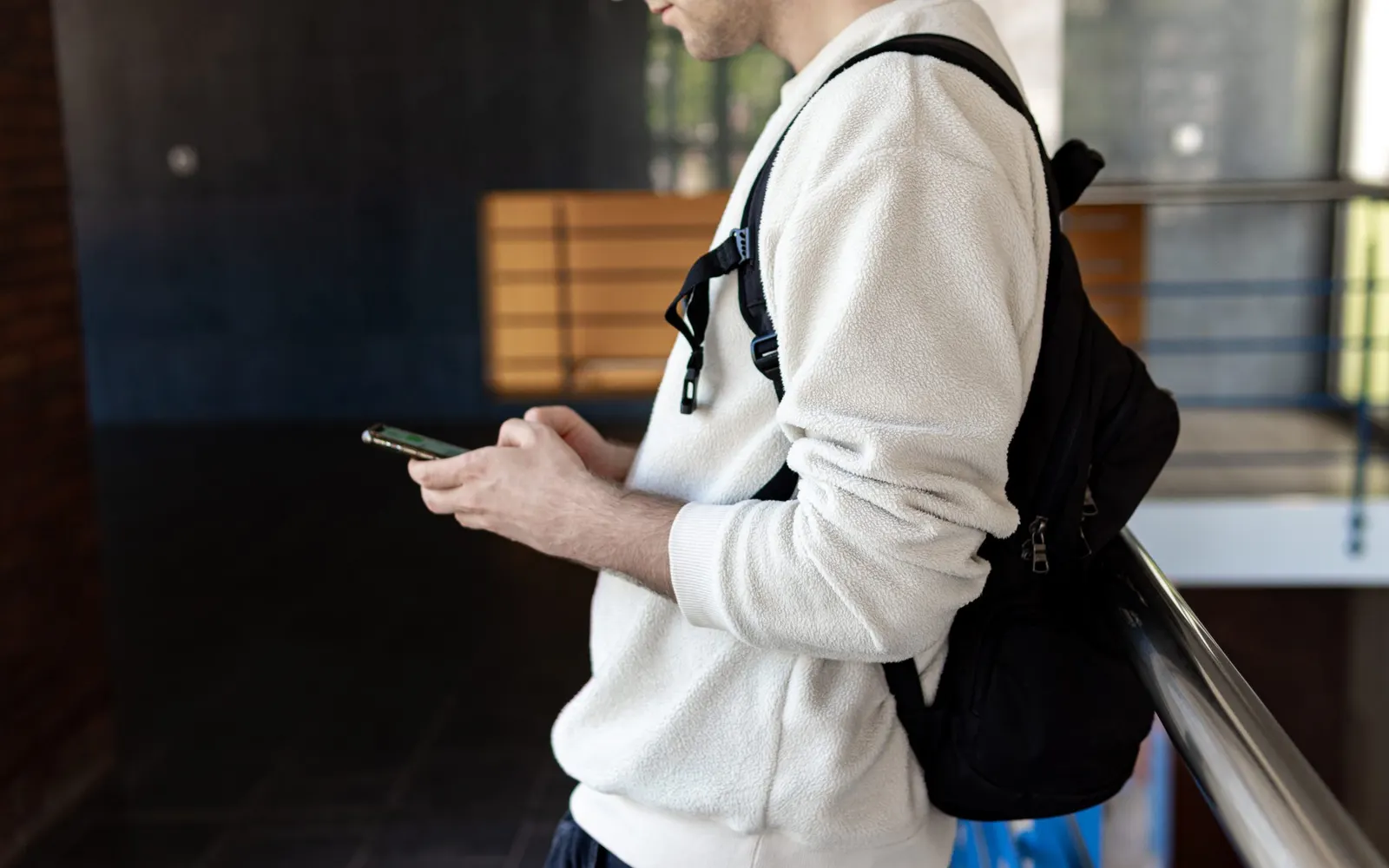A man with a backpack scrolling on his phone
