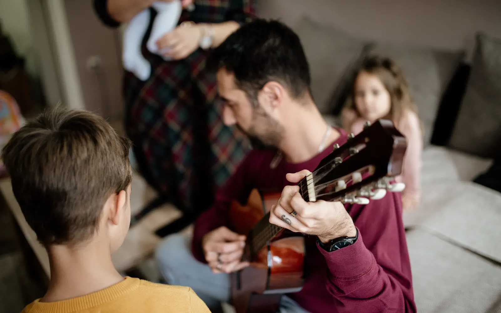 A father playing guitar while his children listen beside him