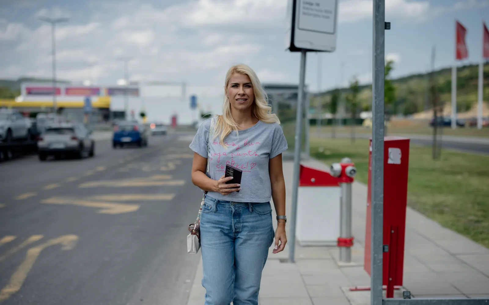 A woman walking along a city street with her phone in hand