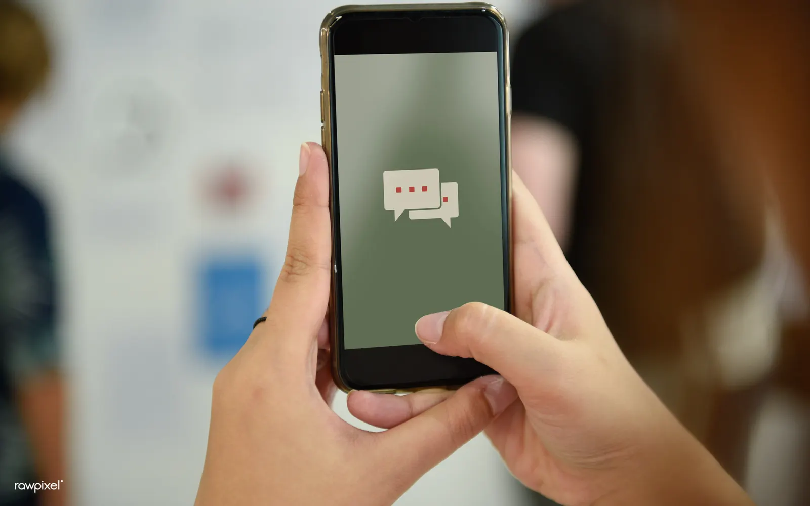 Two hands holding a smartphone showing a simple chat icon